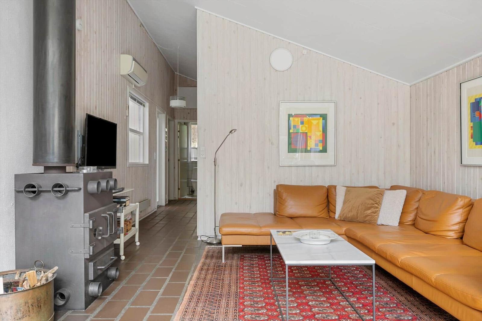 Wohnzimmer mit Leder Sofa, Kaminofen und Holzwandverkleidung.