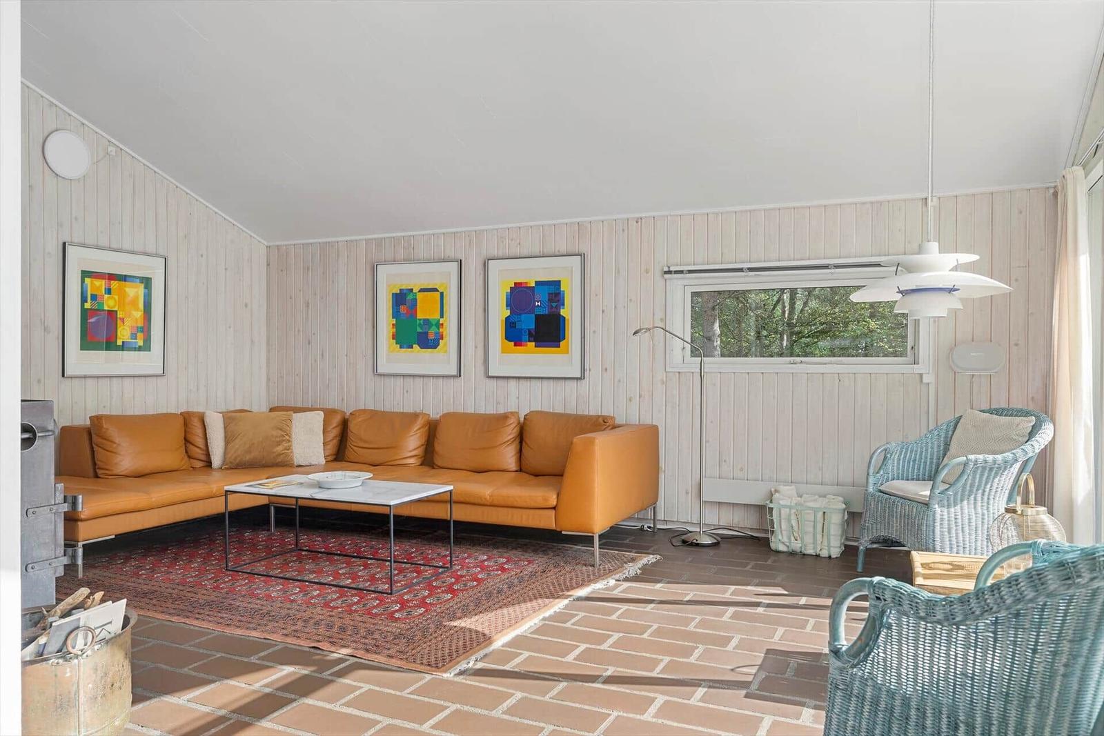 Ein Wohnzimmer mit braunem Sofa, rotem Teppich und blauen Stühlen.