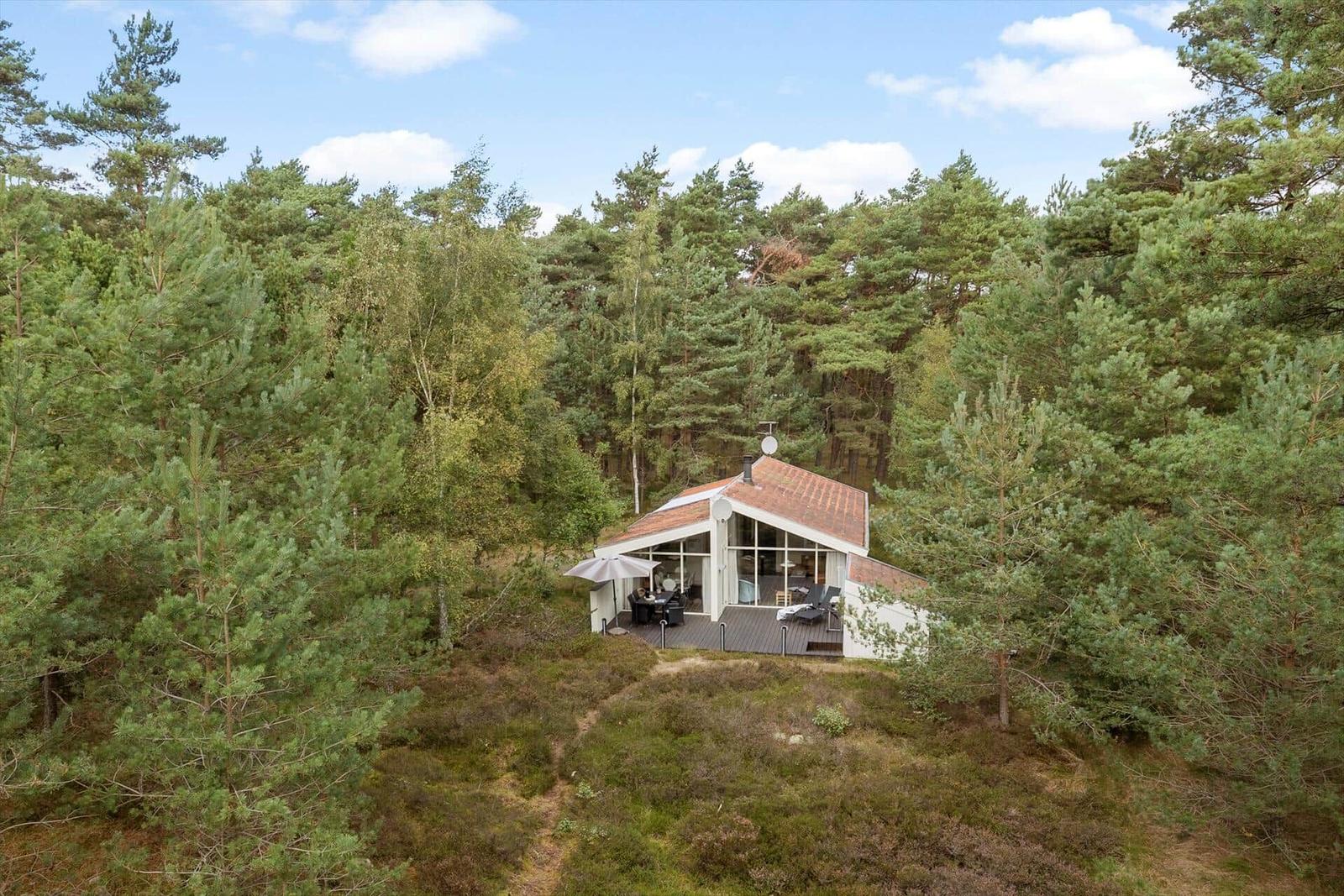 Moderne Hütte mit Terrasse im Wald. Holzterrasse und Sitzgelegenheiten.