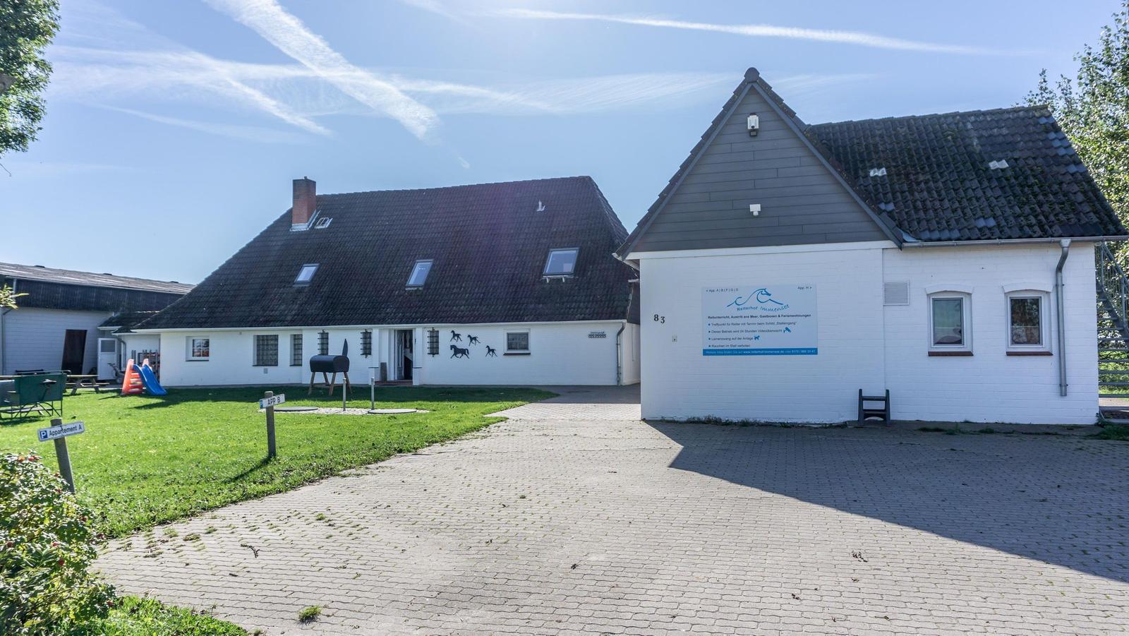 Wohnhaus mit Garten und Spielplatz. Pavillon mit Schild. Pflasterweg führt zur Eingangstür.