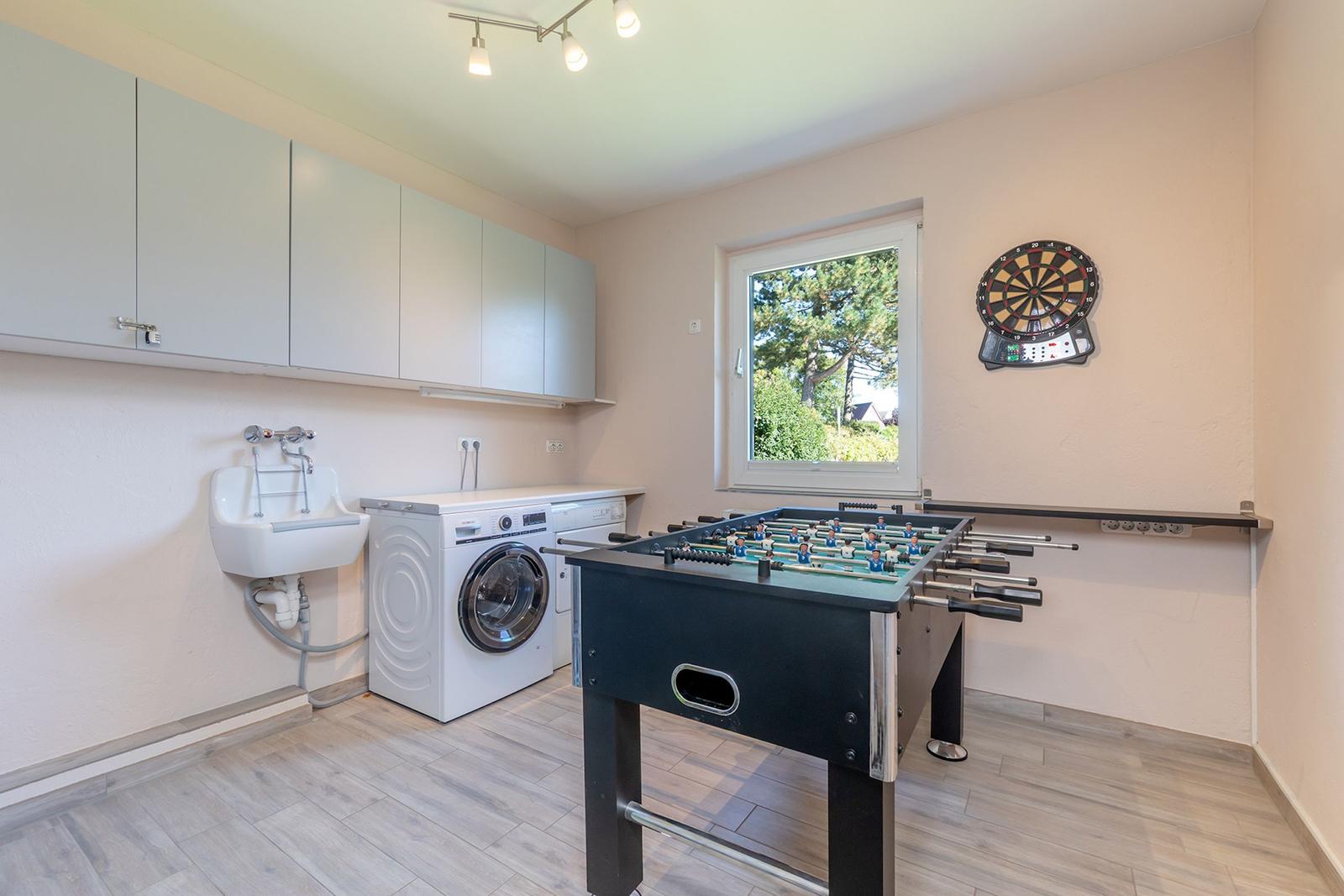 Wohnraum mit Tischfußball, Dartscheibe und Waschmaschine.
