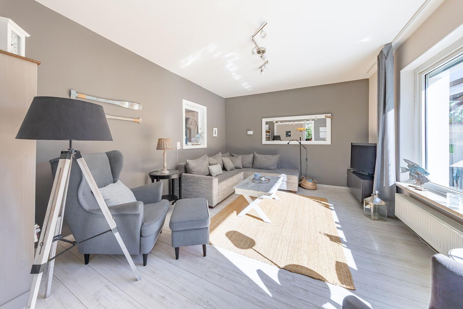 Wohnzimmer mit Sofa, Sessel und Tisch auf Teppich