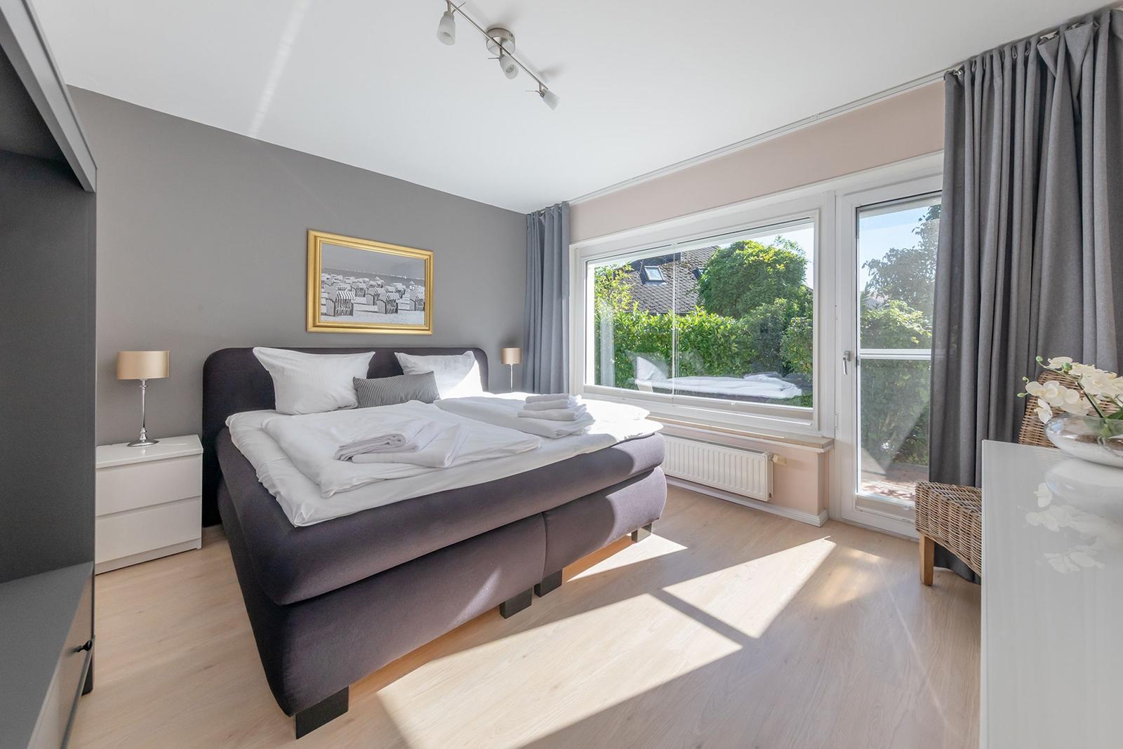 Schlafzimmer mit Doppelbett, Fenster und Gardinen.