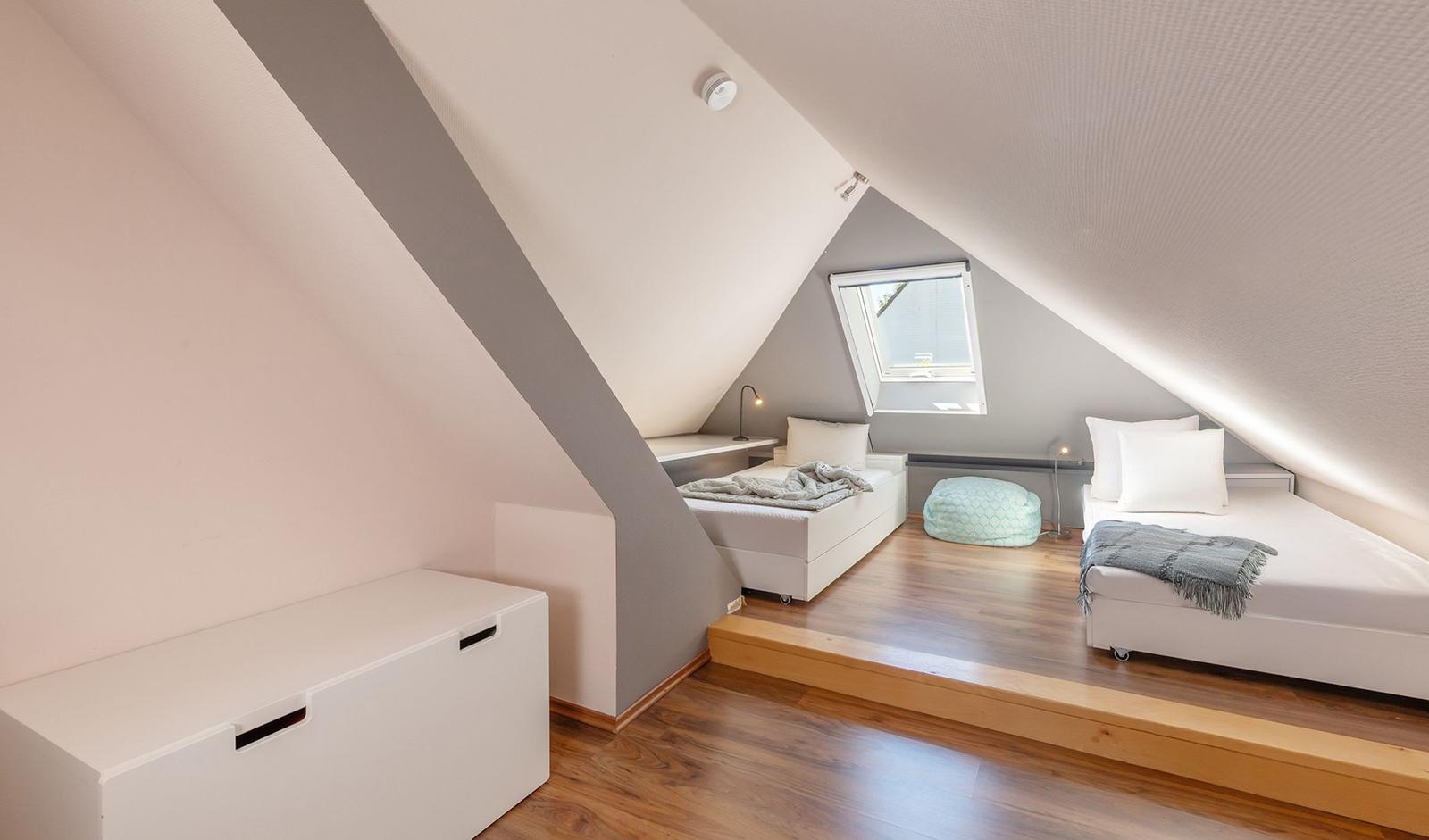 Zwei Schlafplätze unter Dachschrägen mit Dachfenster und Holzboden.
