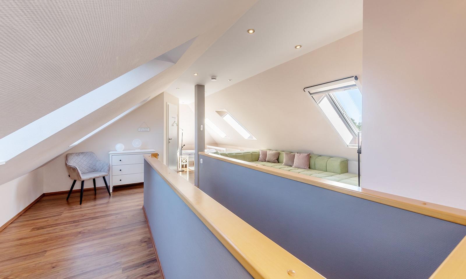 Dachgeschoss mit Sitzbank, Schreibtisch und Dachfenstern.