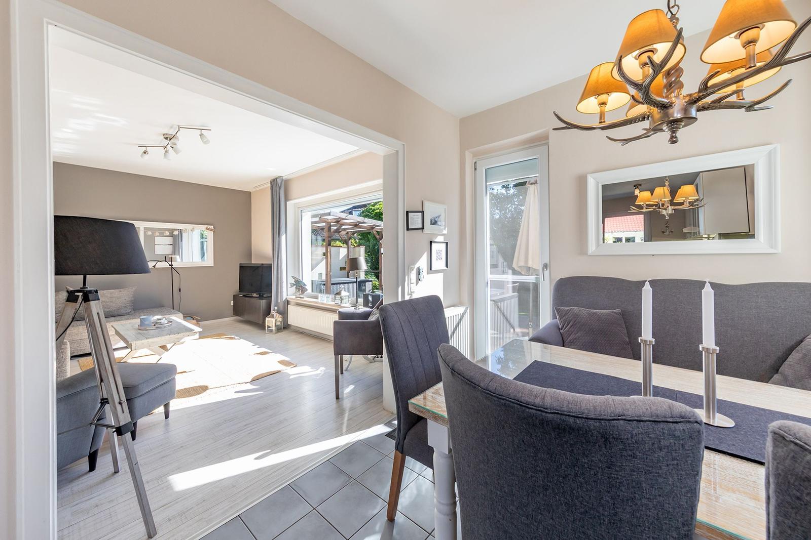 Essbereich mit Tisch und Stühlen, dahinter Wohnzimmer mit Sofa und TV.