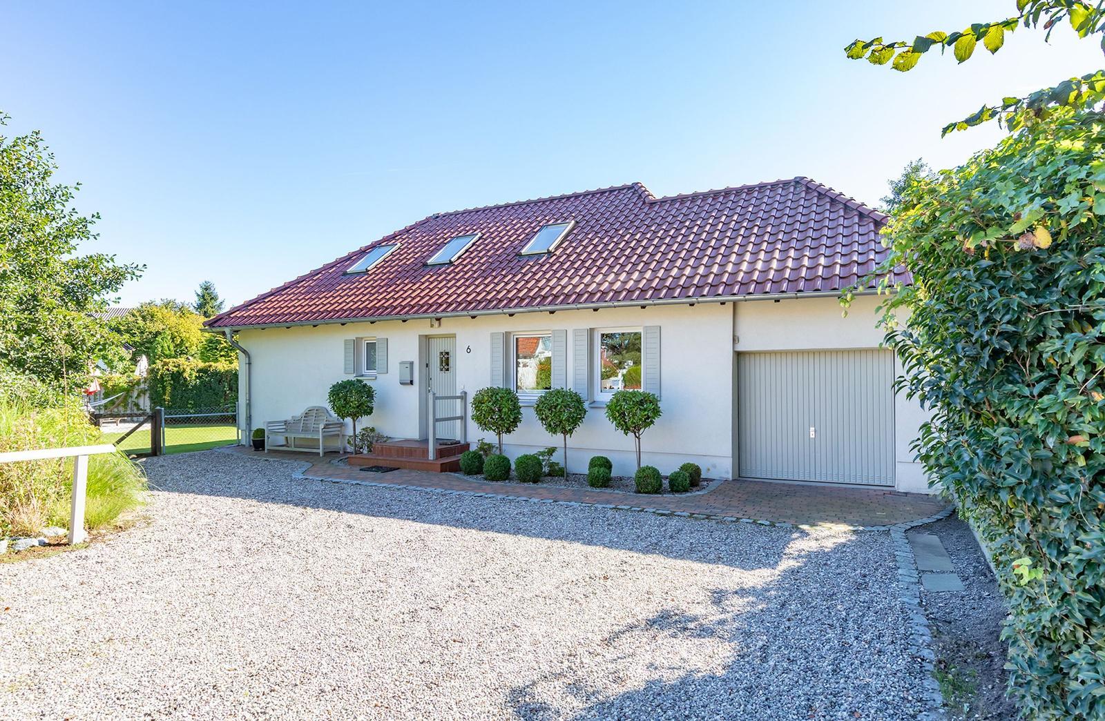 Einfamilienhaus mit Garage, Terrasse und gepflegtem Garten. Dach mit Dachfenstern.