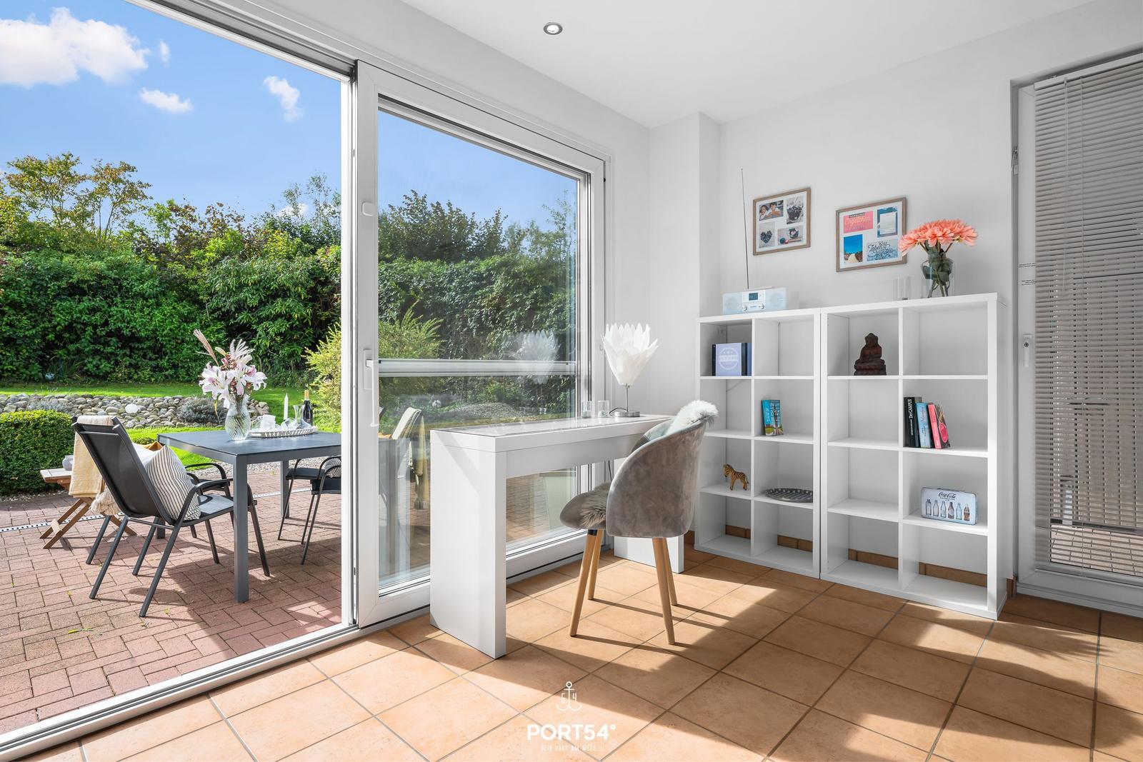 Helle Arbeitszimmer mit Schreibtisch, Bücherregal und Terrasse mit Gartenblick.