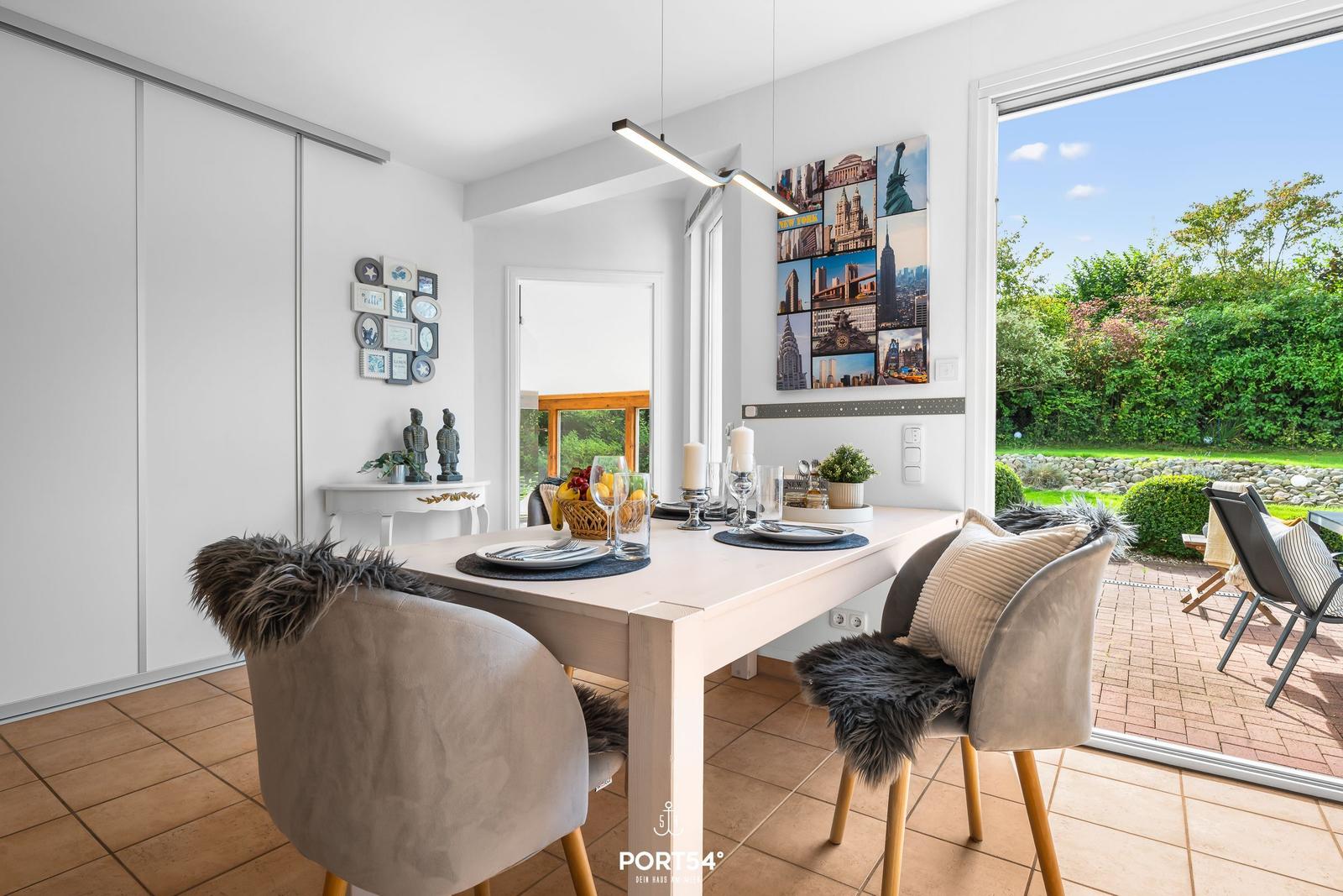Essbereich mit Tisch, Stühlen und Blick auf Garten.
