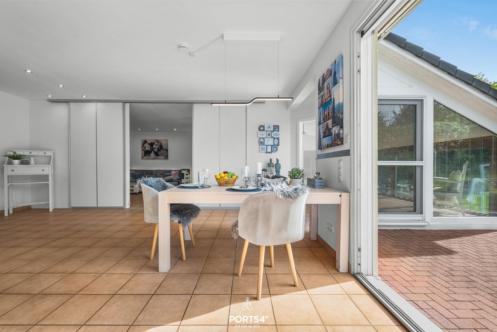 Esszimmer mit Tisch, Stühlen und Blick auf Terrasse.