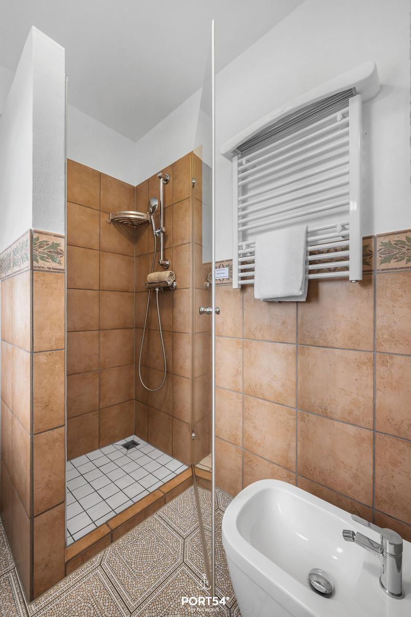 Bad mit Dusche, Bidet und Heizkörper. Fliesen in Terrakottaton.