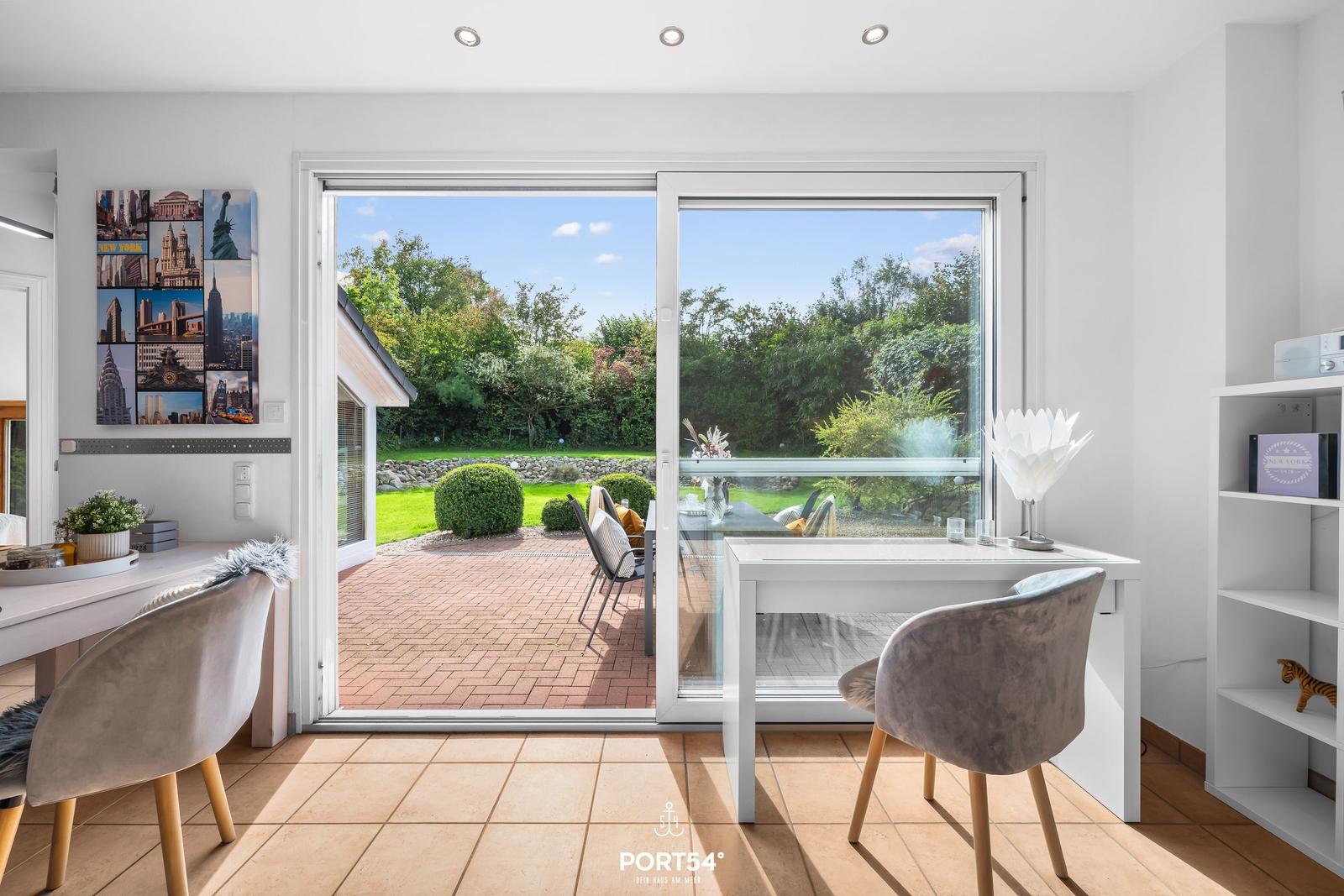 Raum mit Schreibtisch, Sitzgelegenheit und Blick auf den Garten.