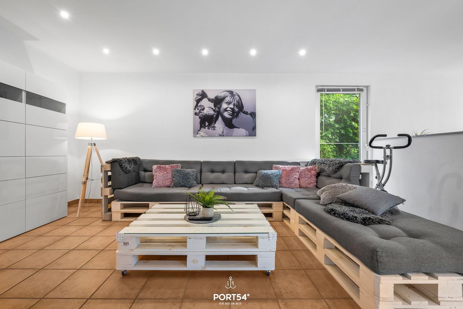 Wohnraum mit Sofa auf Paletten, Tisch und Wandbild.