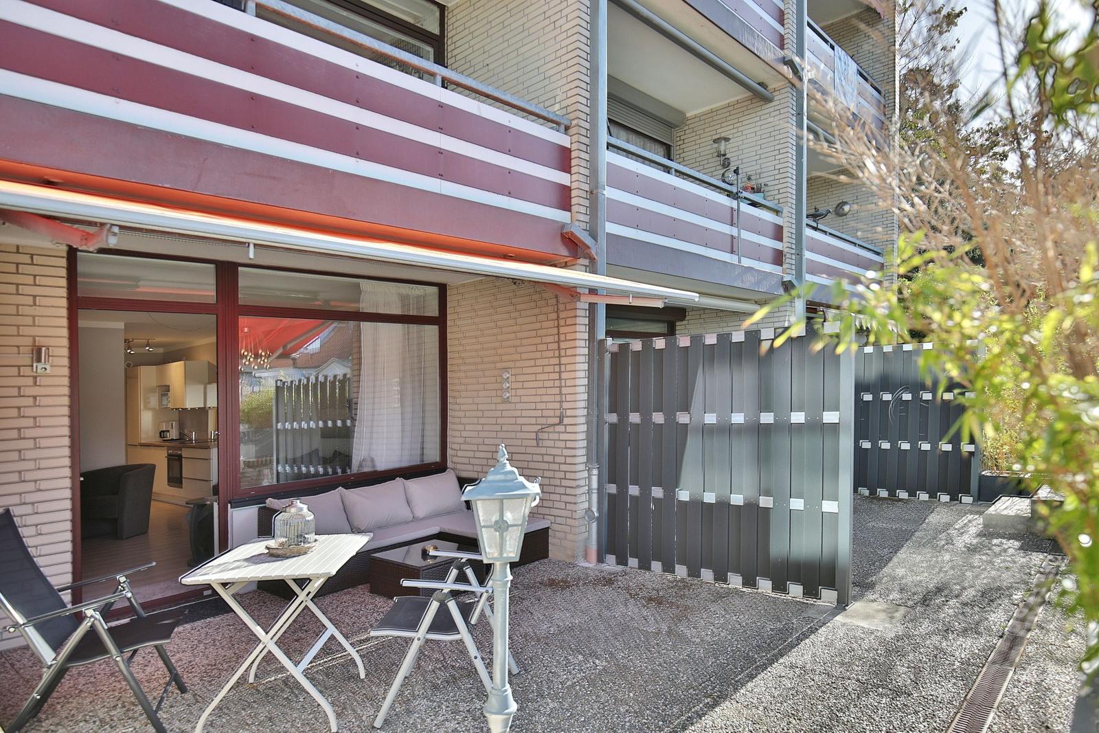 Terrasse mit Sitzgelegenheit und Blick in die Küche. Hinterhof mit Gittertor.