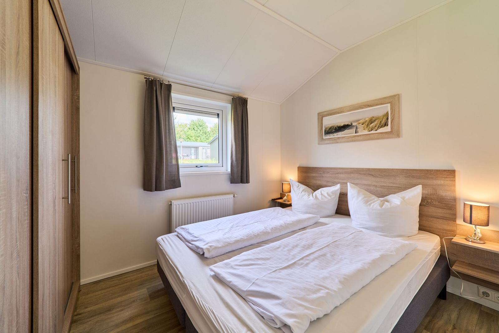 Schlafzimmer mit Doppelbett, Kleiderschrank und Fenster mit Blick.