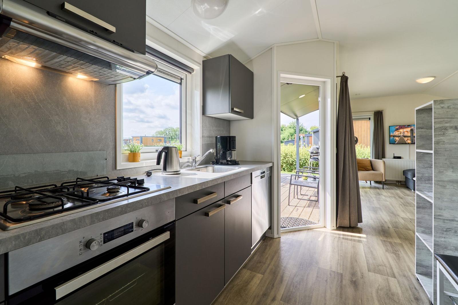 Küche mit Fenster, Spüle, Kochfeld und Blick auf Terrasse