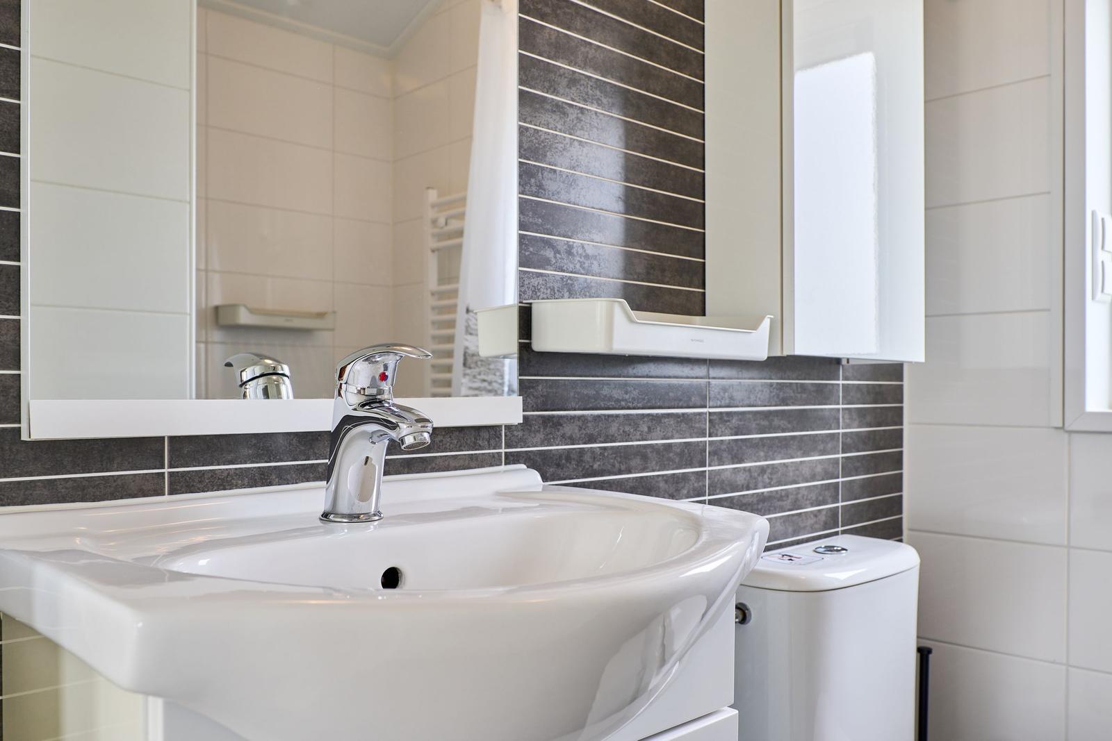 Waschbecken mit Spiegel und Toilette in Badezimmer