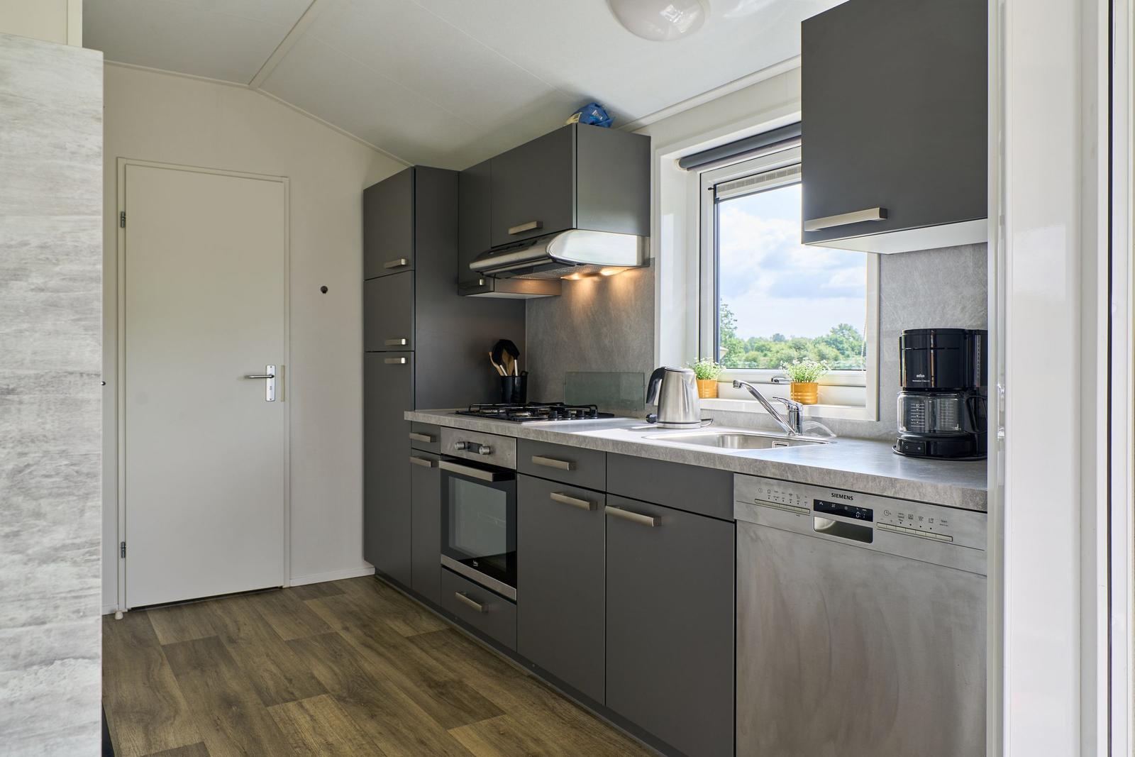 Küche mit grauen Schränken, Spüle und Fensterblick.