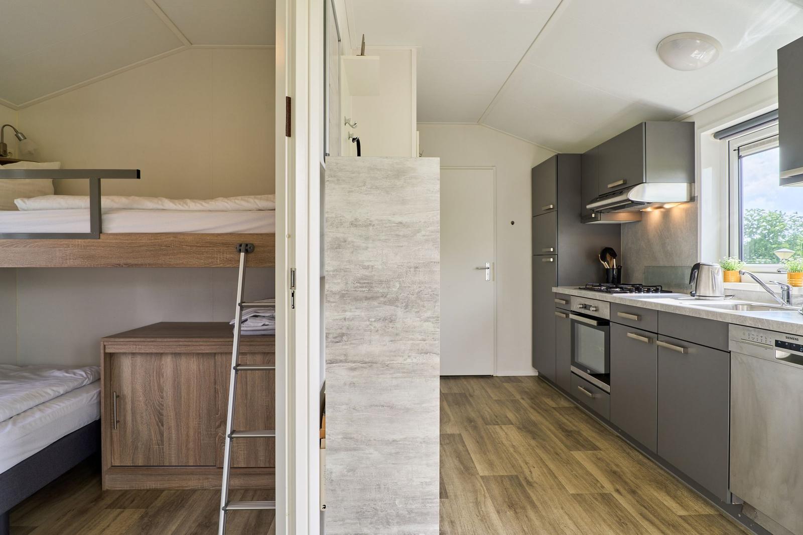 Küche mit Dunstabzug und Fenster. Schlafbereich mit Doppelstockbett.
