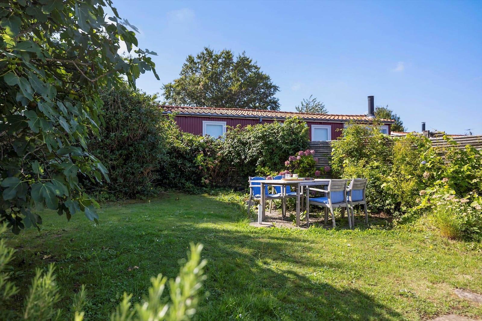 Red garden house with table and chairs in the green garden.