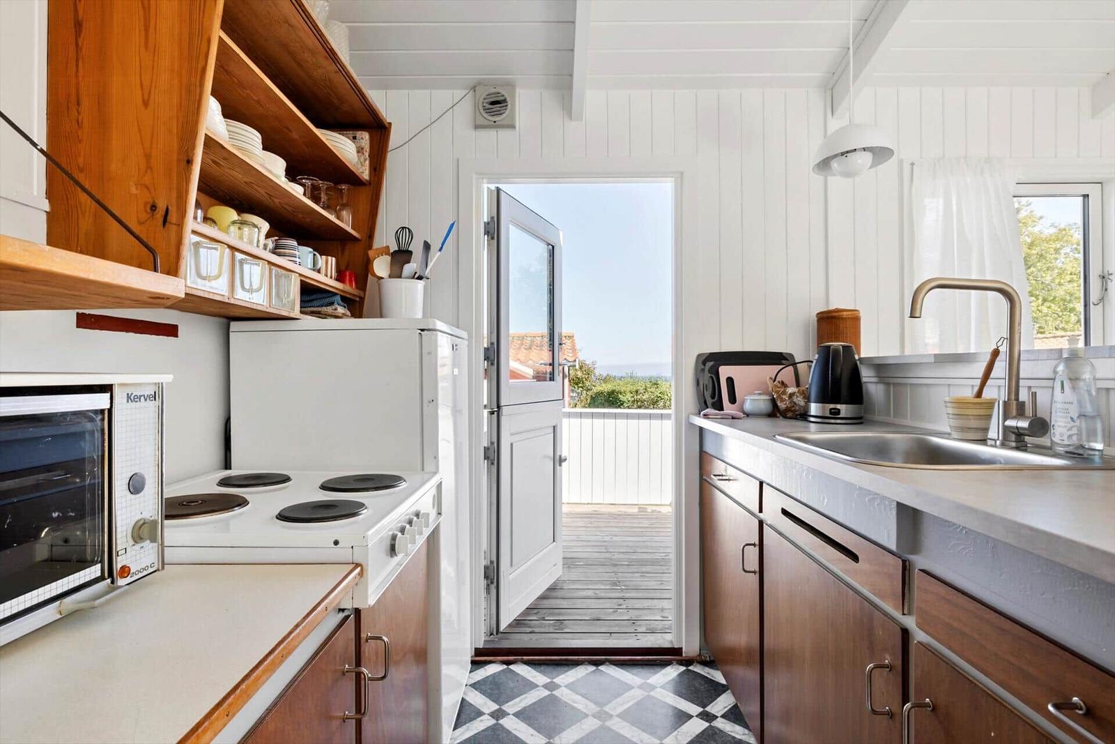 Kitchen with wooden shelves, refrigerator, and view of balcony