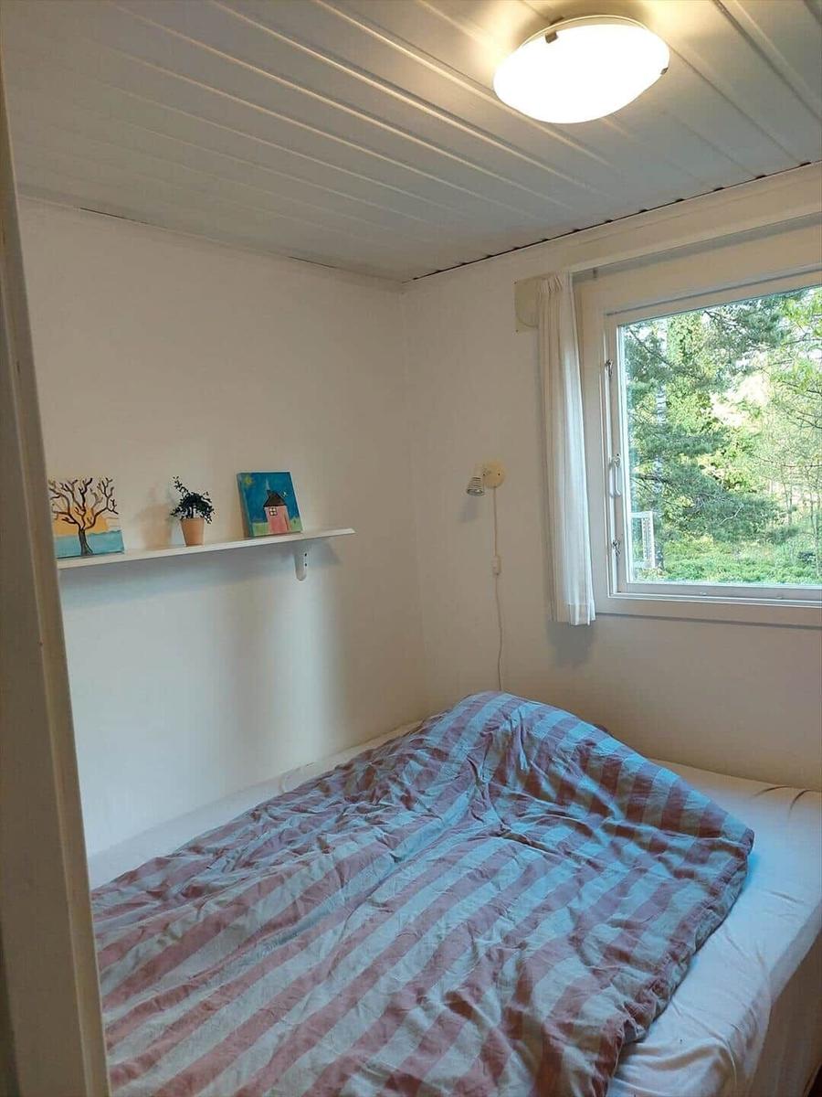 Schlafzimmer mit Bett, Fenster und Regal mit Dekoration.