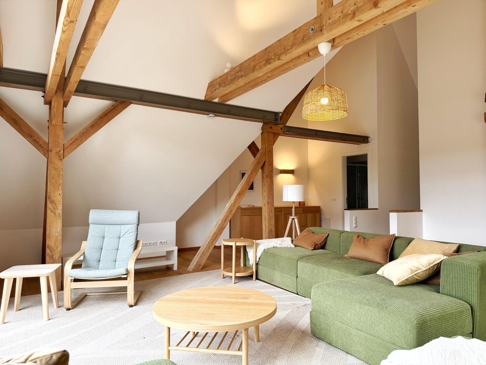 Wohnzimmer mit grünem Sofa, Holzrahmen und runden Tisch.