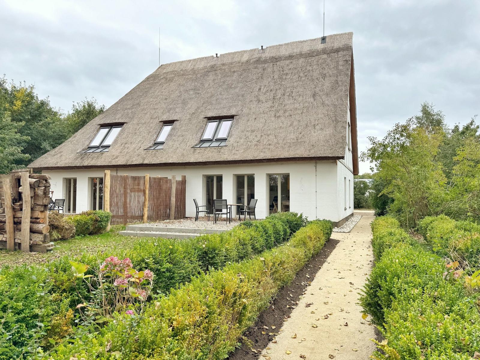 Haus mit Strohdach, Terrasse und gepflegtem Gartenweg.