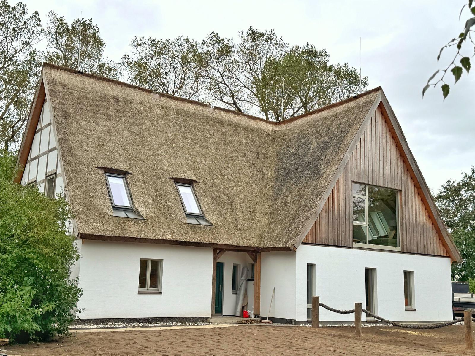 Haus mit strohgedecktem Dach und Holzfassade