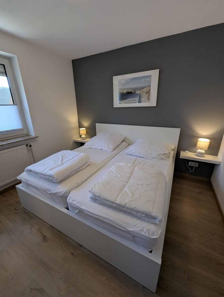 Schlafzimmer mit Doppelbett, zwei Nachttischen und Wandbild.