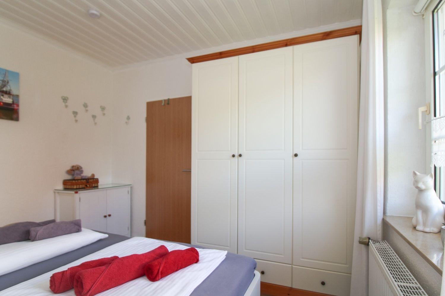 Schlafzimmer mit Bett, Kleiderschrank und Fenster mit Katzenfigur.