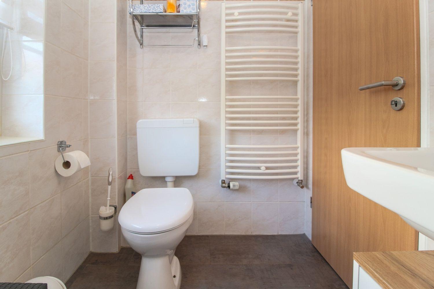 Badezimmer mit Toilette, Handtuchwärmer und Waschbecken.