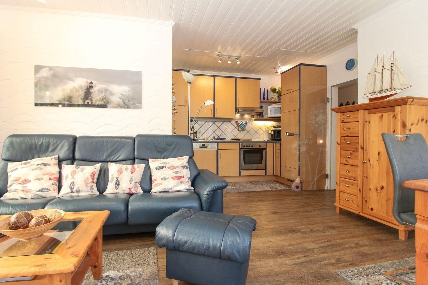 Wohnzimmer mit Sofa, Küchenbereich und Holzmöbel