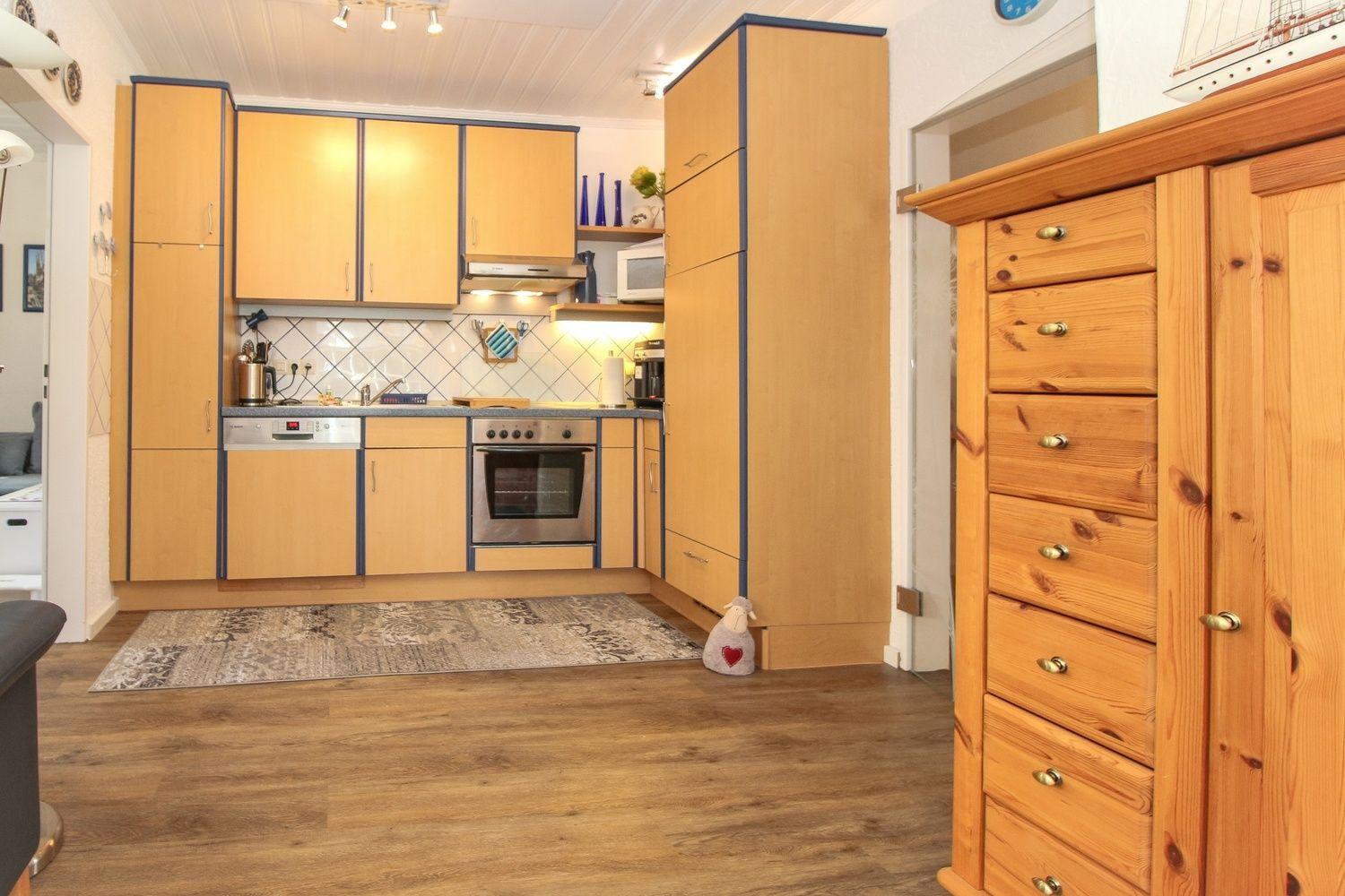 Küche mit Holzmöbeln, Edelstahlgeräten und Fliesenwand.