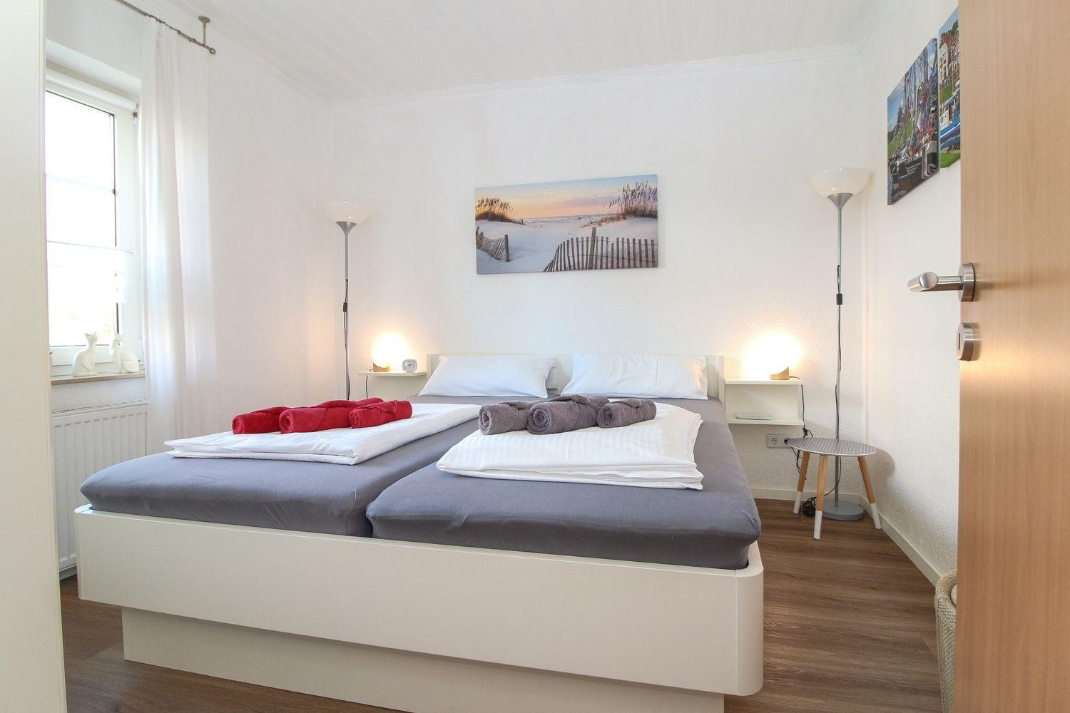 Schlafzimmer mit Doppelbett, zwei Stehlampen und Wandbild.