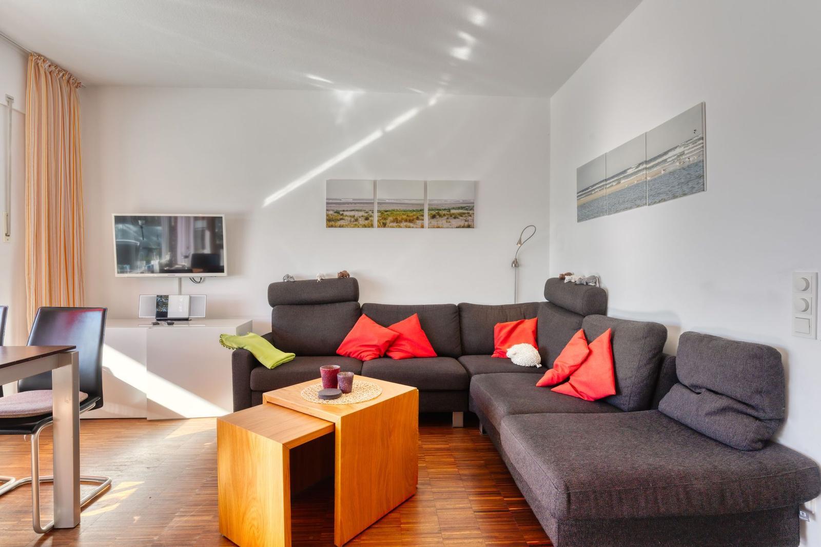 Wohnzimmer mit Sofa, Fernseher und Holztisch.