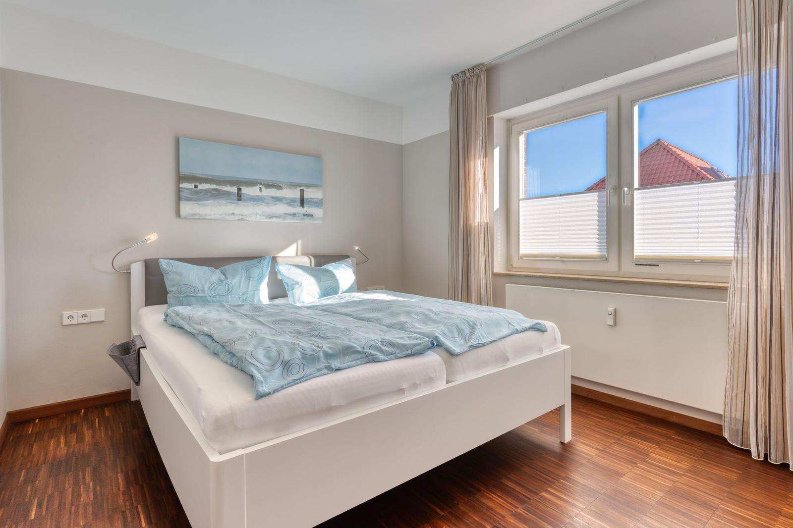 Schlafzimmer mit Doppelbett, Wandbild und Fenster mit Blick.