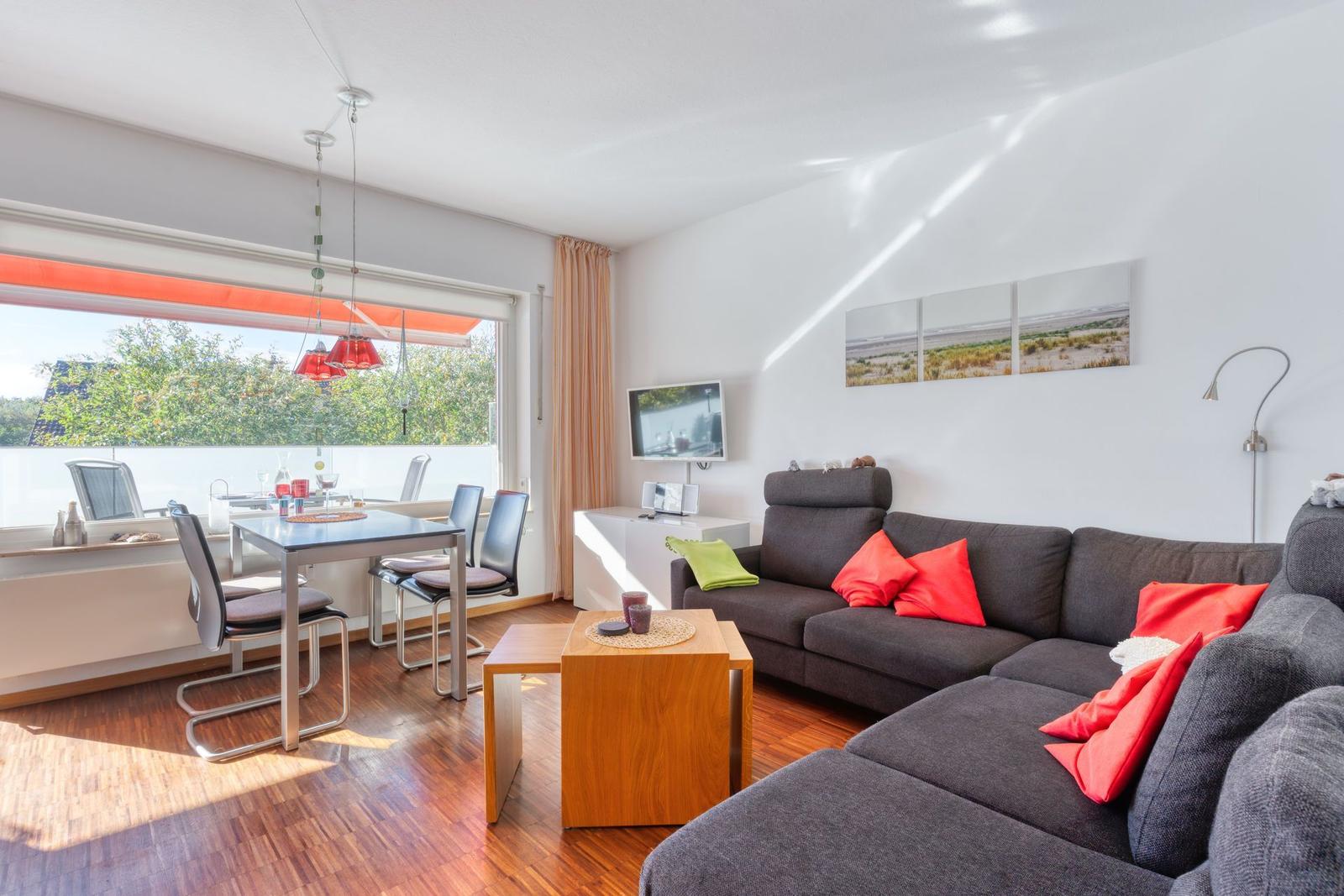 Wohnzimmer mit Sofa, Esstisch und Blick auf Balkon