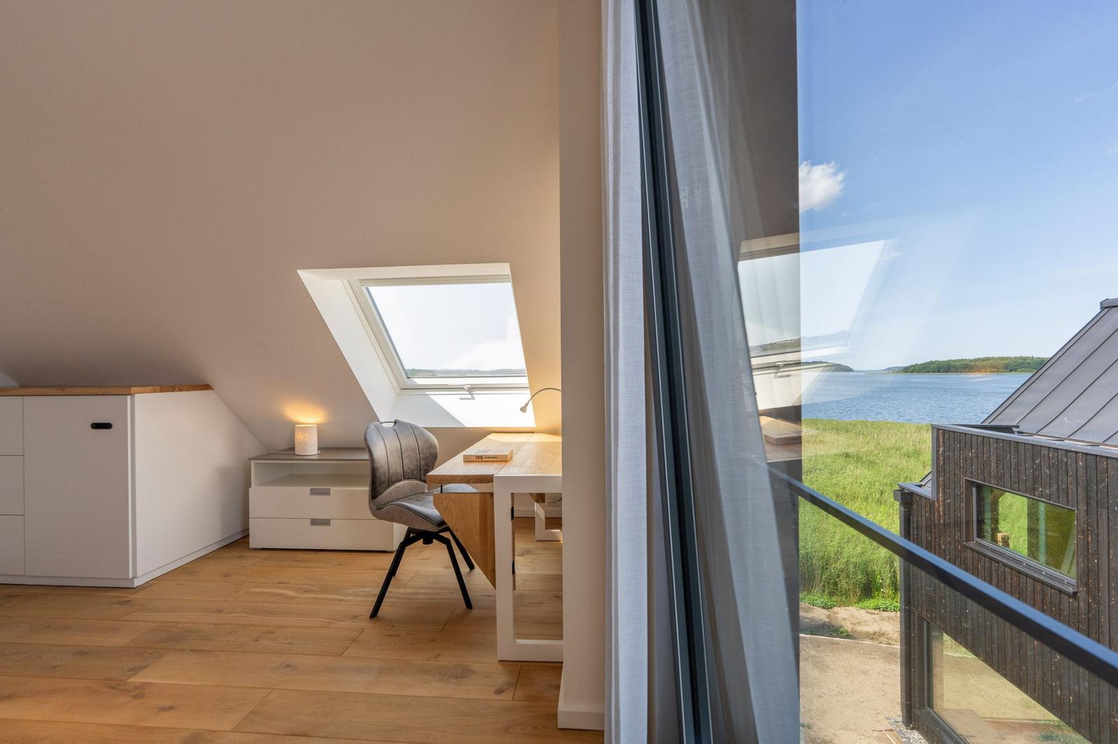 Dachgeschosszimmer mit Schreibtisch und Blick auf See