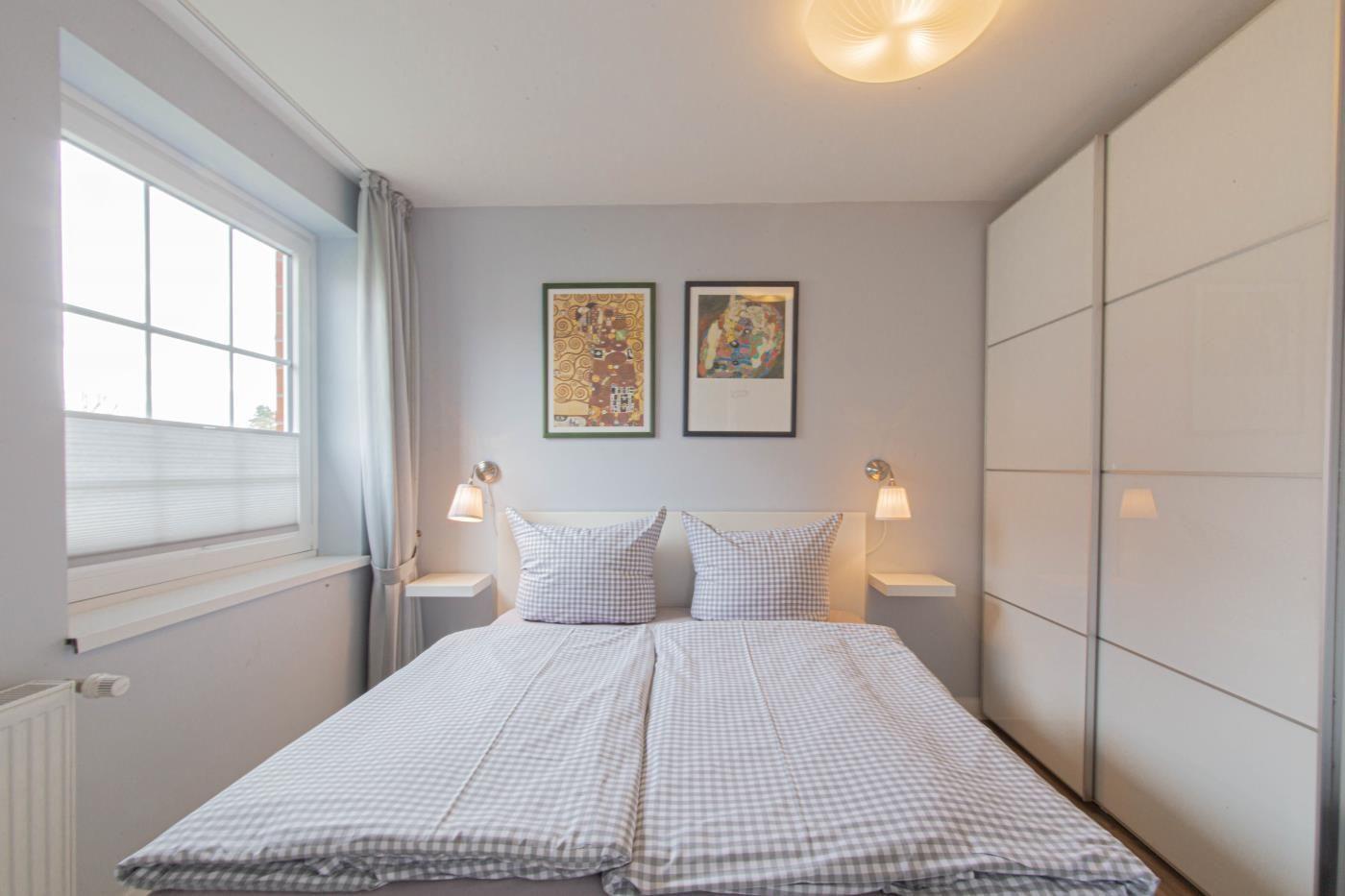 Schlafzimmer mit Doppelbett, Fenster und weißen Schwebetüren.