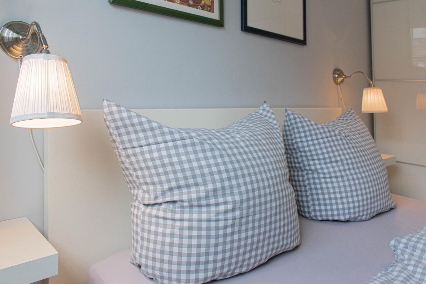 Ein Bett mit karierten Kissen und Wandlampen.