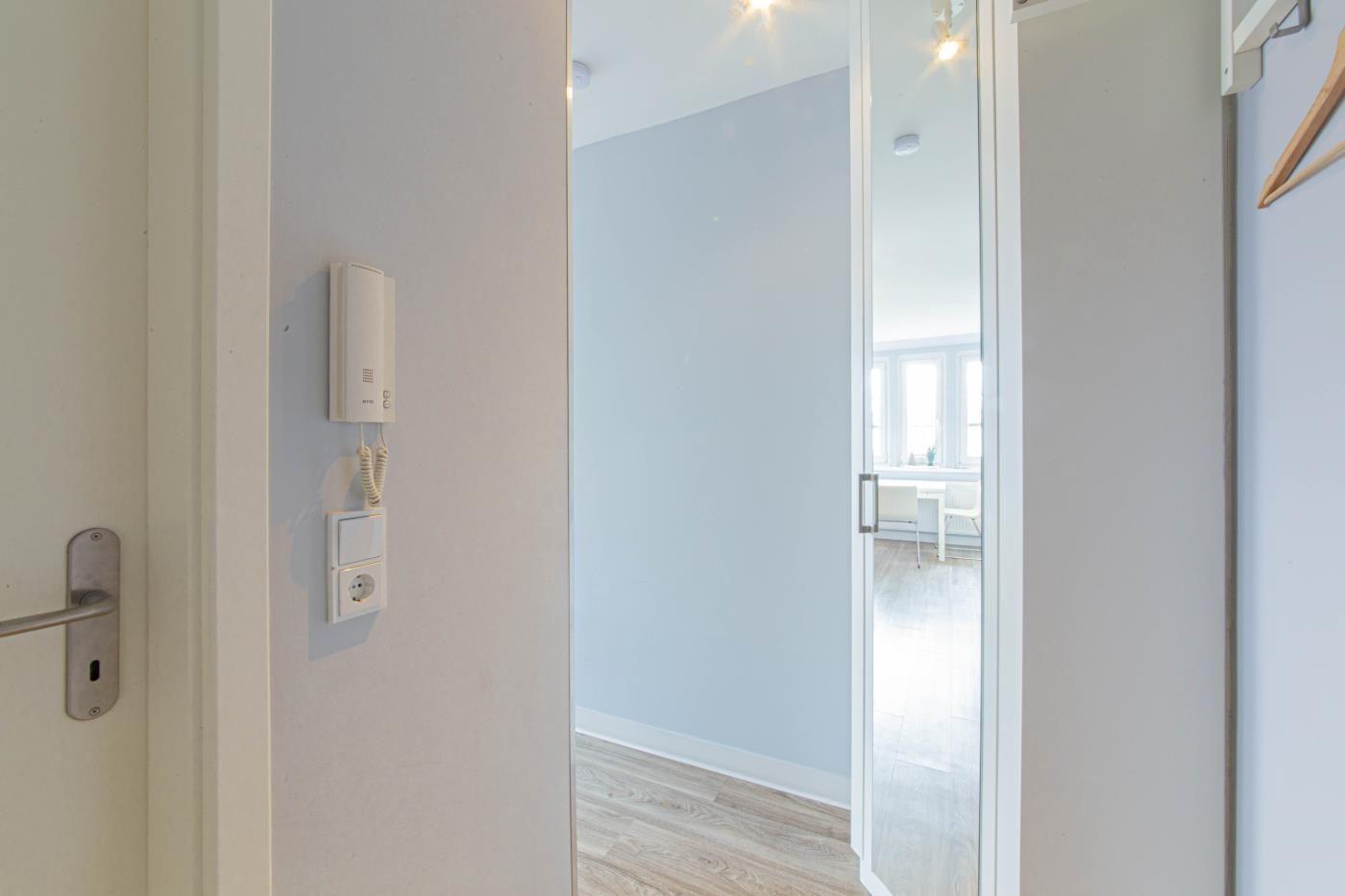 Eingangsbereich mit Glaswand und Blick in Wohnbereich mit Tisch und Stühlen.