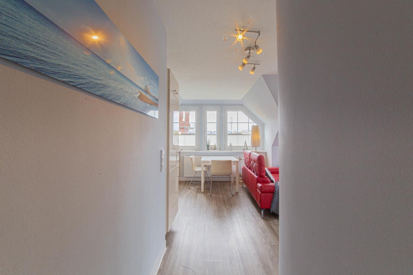 Ein Raum mit rotem Sofa, Tisch und Fenstern.