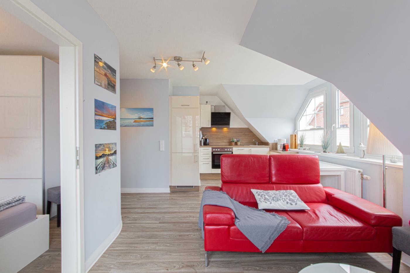 Wohnung mit rotem Sofa, Küche und Schlafzimmer im Dachgeschoss.
