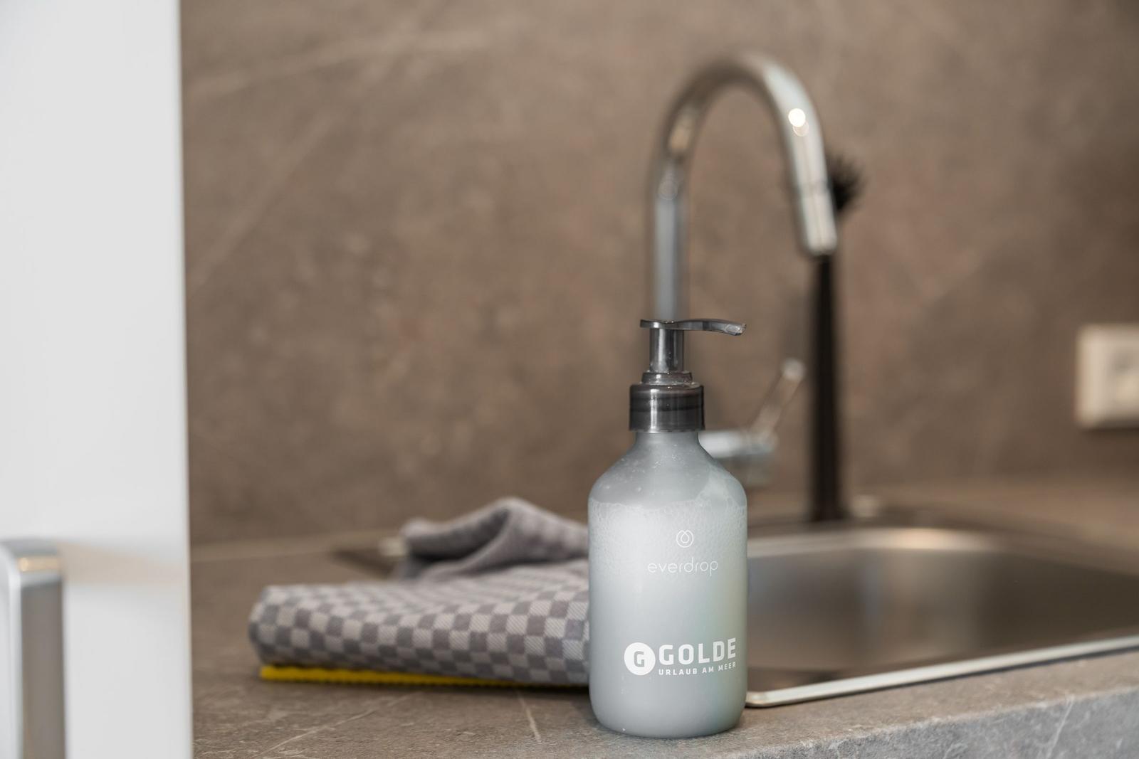 Soap dispenser with foam next to sink and towel