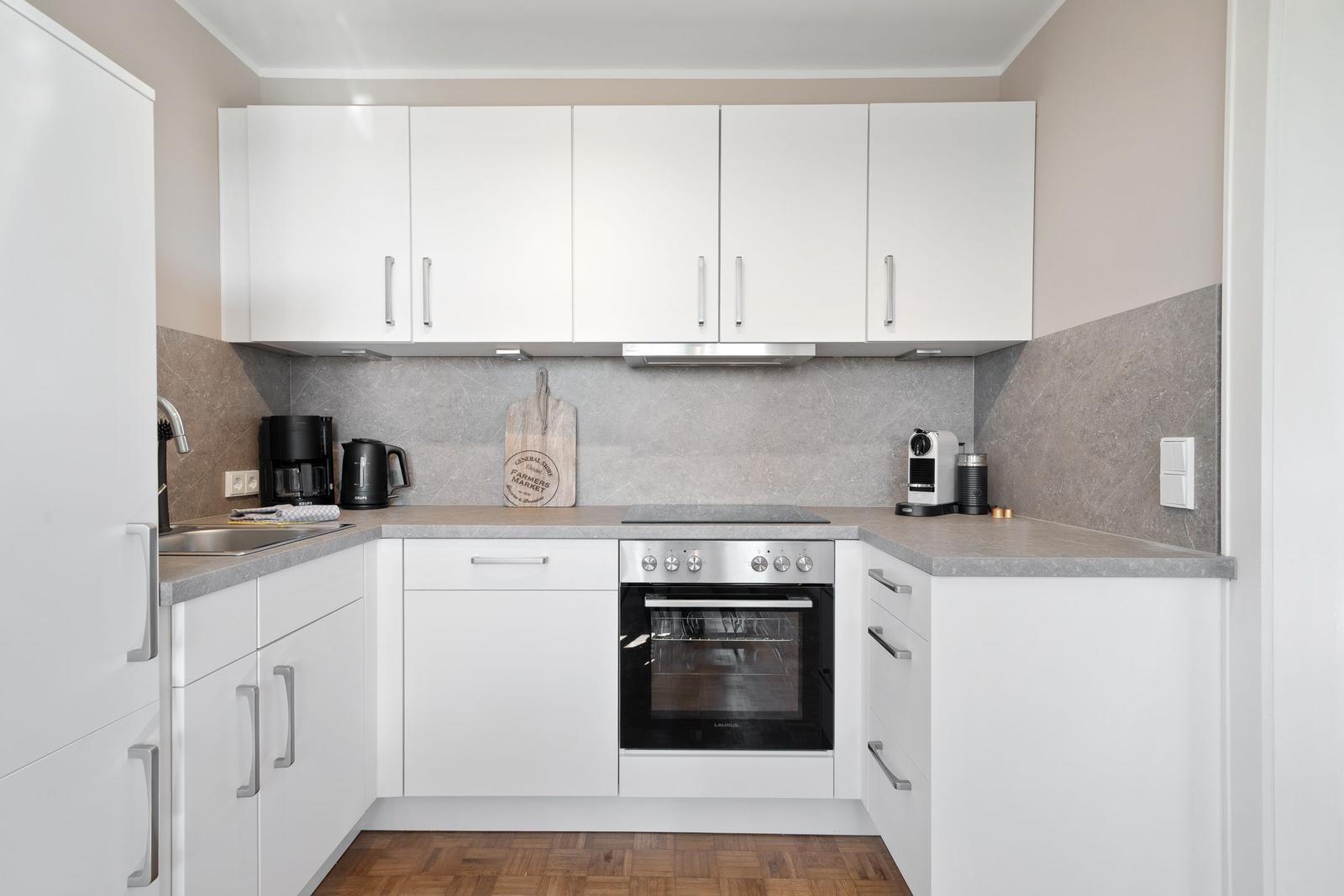 Kitchen with white cabinets, stainless steel stove, and stone countertop.