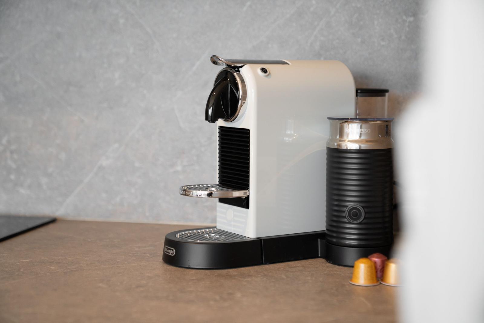 Nespresso coffee machine with milk frother and capsules on kitchen counter.