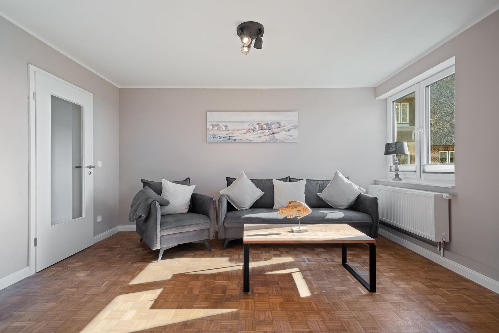 Living room with gray sofa, wooden floor, and window.