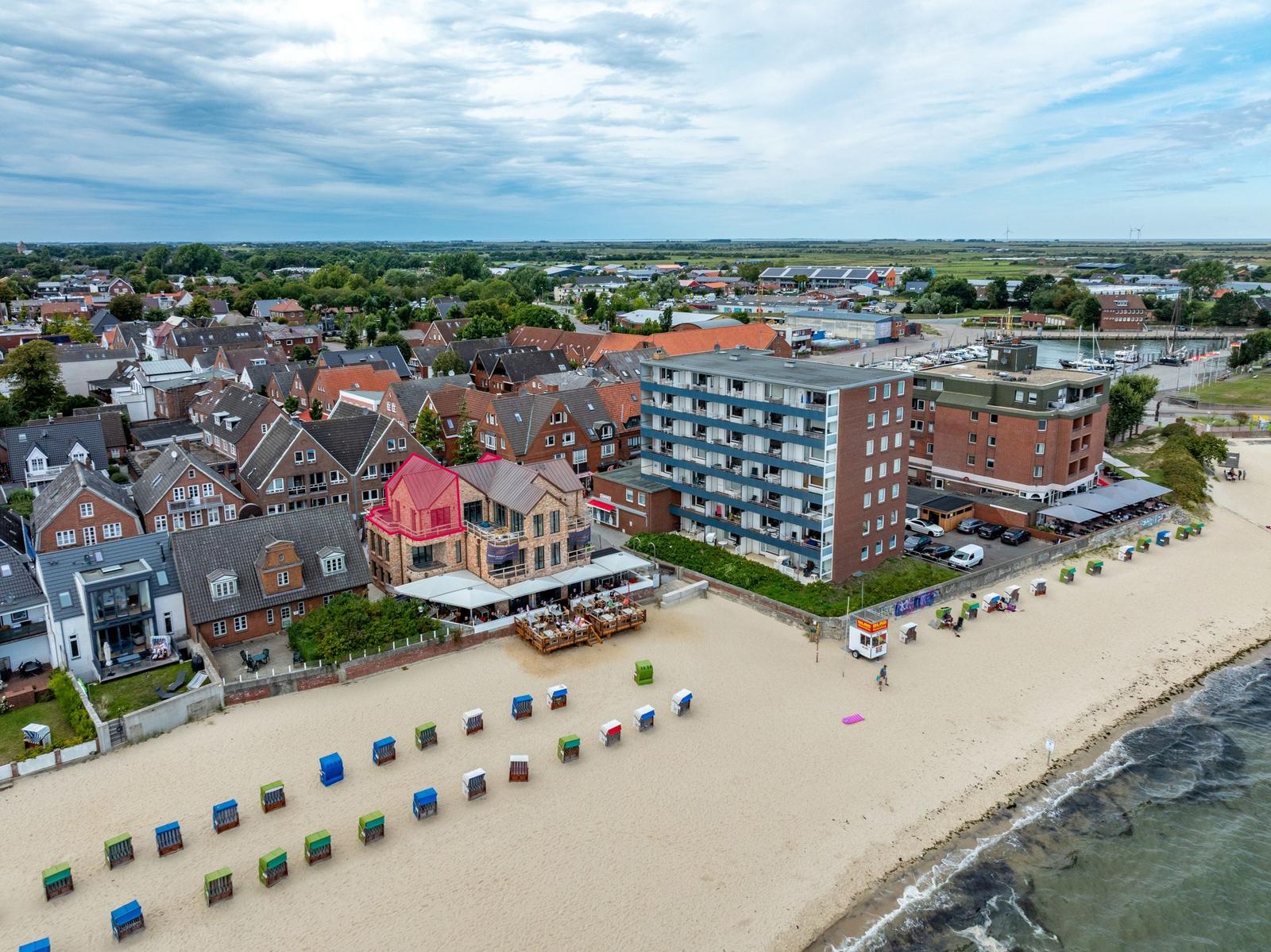 Strandpromenade mit bunten Strandkörben und Hotels direkt am Meer.