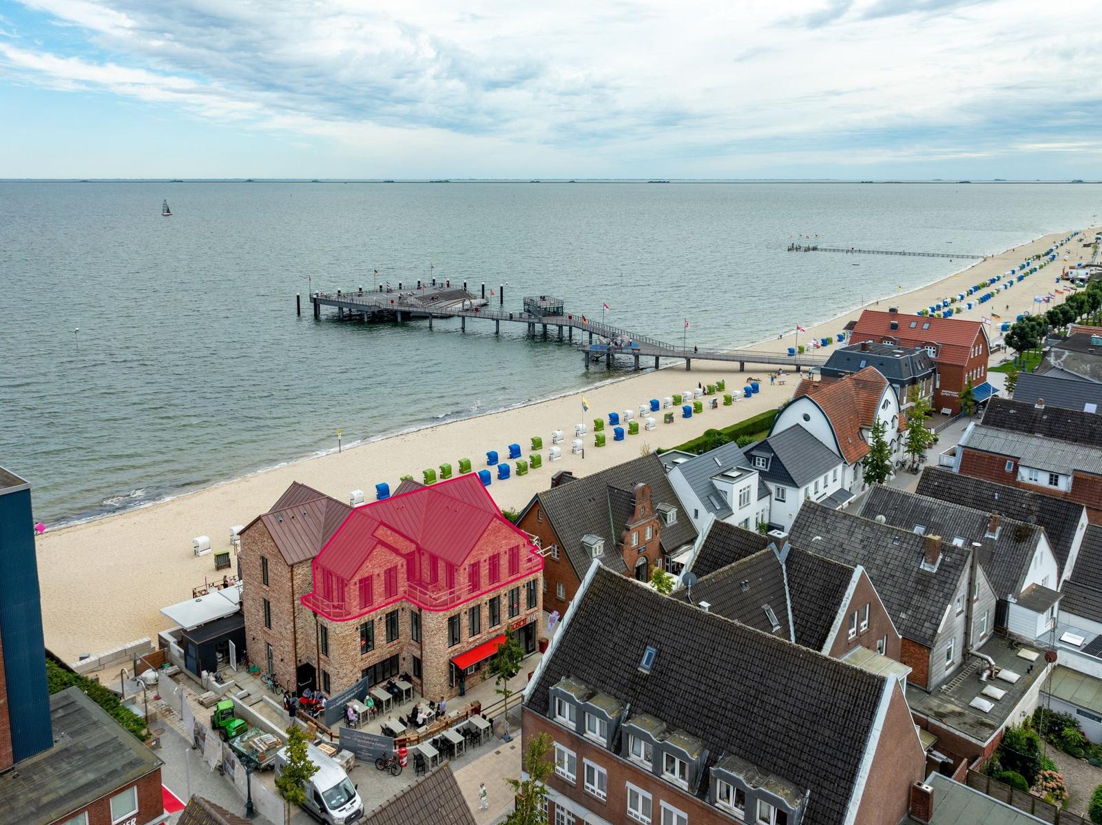 Haus mit rotem Dach an Strand, Blick auf Pier und See.